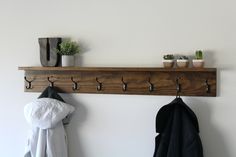 a coat rack with hooks and two coats hanging from it's sides next to a potted plant