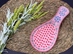 a pink and blue ceramic brush next to some green plants on a wicker basket