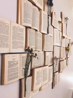 several open books are hung on the wall with flowers attached to them and tied together