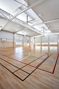 an empty gym with hard wood flooring and basketball hoop on the wall in the center