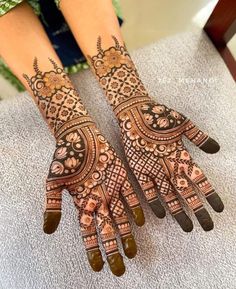 two hands with henna tattoos on them, one is showing off the intricate design