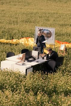 two people sitting at a table in the middle of a field