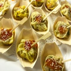 small wooden spoons filled with dumplings covered in sauce