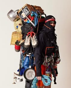 a man carrying a large amount of items on top of his back while wearing skis