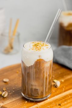 an iced coffee drink with whipped cream and almonds on the side, sitting on a wooden cutting board