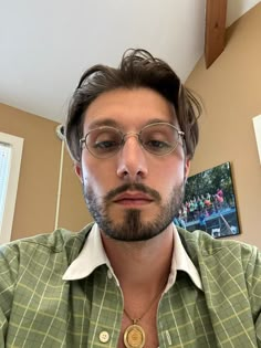 a man with glasses and a beard wearing a green shirt is looking at the camera