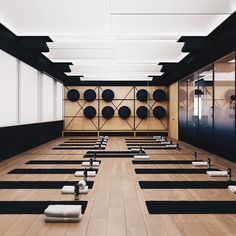 rows of black and white yoga mats lined up on the floor in front of mirrors