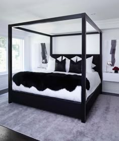 a black and white bedroom with four poster bed in the middle, carpeted floor