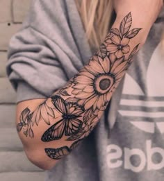 a woman's arm with flowers and butterflies tattooed on the side of her arm