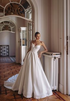 a woman in a white wedding dress leaning against a wall