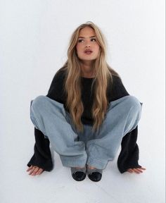 a woman is sitting on the floor with her legs crossed and looking at the camera