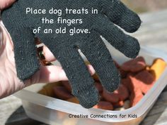 a person holding up a black glove in front of a plastic container filled with dog treats