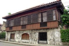 an old building with wooden shutters and iron bars on the windows is next to a street