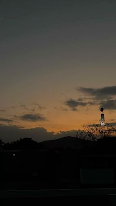 the sun is setting behind a tower with a clock on it's side and clouds in the background