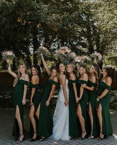 a group of women in green dresses standing next to each other with their arms in the air