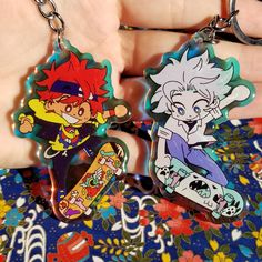 two cartoon keychains are shown in the palm of someone's left hand