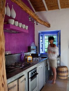 a woman standing in a kitchen next to an oven and counter top with pots on it