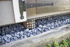 a close up of a metal grate on the side of a building with rocks