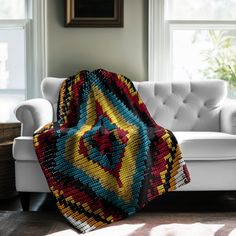 a living room with a white couch and a colorful blanket on the back of it