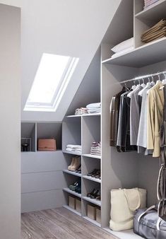 an attic closet with shelves, clothes and shoes on the bottom shelf is open to reveal a skylight