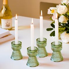 four candles are sitting on a table next to some wine bottles