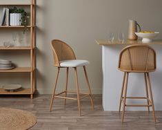 two wicker bar stools in front of a counter with plates and glasses on it