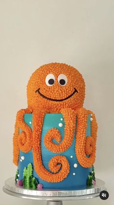 an octopus cake is decorated with orange icing and blue frosting on a silver platter