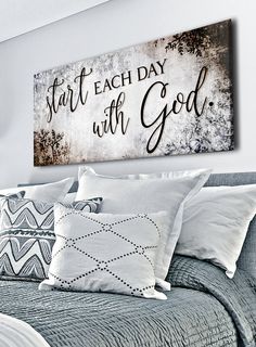 a bed with white pillows and a wooden sign above it that says start each day with god