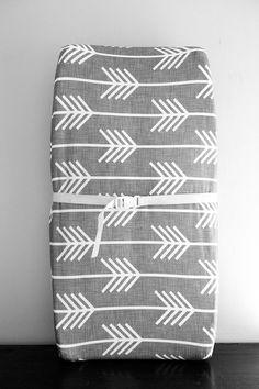 a black and white photo of a blanket with an arrow pattern on the front, tied to a wooden table