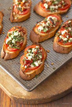 small toasted breads topped with tomatoes and feta cheese on a baking sheet