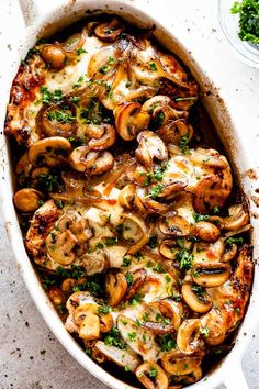 chicken and mushroom casserole with parsley in a white dish on a table