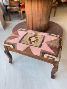 a small wooden bench with a pink and brown blanket on it's backrest