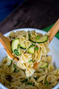 a wooden spoon full of noodles and cucumbers