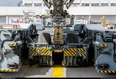 an industrial machine is parked in front of a building with yellow and black stripes on it