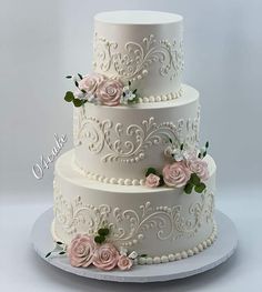 a three tiered wedding cake with pink flowers on top and white icing around the edges