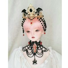 a doll with pink hair wearing a black and gold tiara on top of it's head