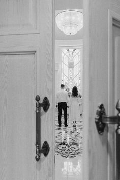 a man and woman standing in front of a door with the reflection of them on the floor