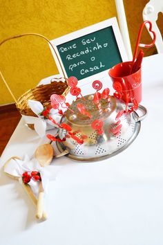 a white table topped with a metal colander filled with candy canes and marshmallows