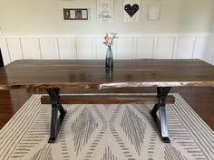 a wooden table sitting on top of a rug next to a vase filled with flowers