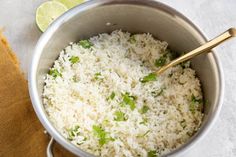 rice and cilantro in a silver pot with a wooden spoon next to it