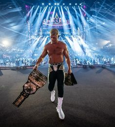 a man with no shirt on walking in front of a crowd at a wrestling match