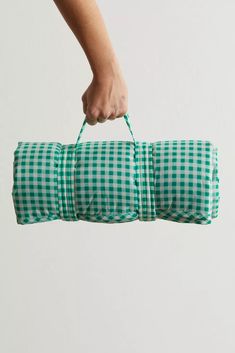 a person is holding a green and white checkered duffel bag in the air