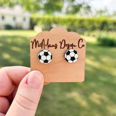 a person holding up a pair of soccer ball earrings