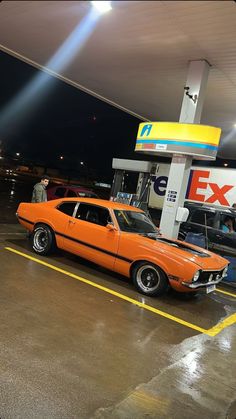 an orange car is parked at a gas station