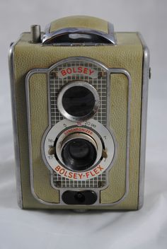 an old style camera sitting on top of a white table