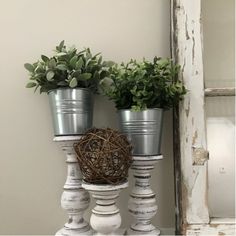 two potted plants are sitting on top of some white candlesticks and one is holding a bird's nest