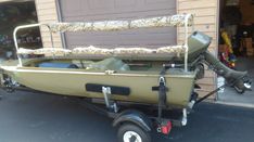 a small boat is parked in front of a garage with a canopy on the back