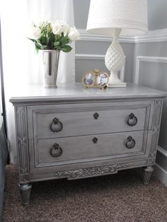 a white dresser sitting next to a window