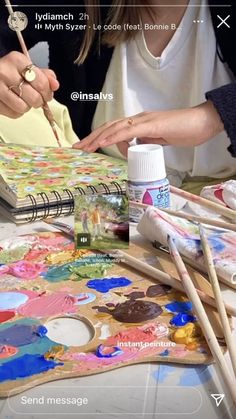 a woman is painting on an easel with paintbrushes