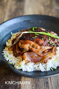 a black plate topped with rice and meat